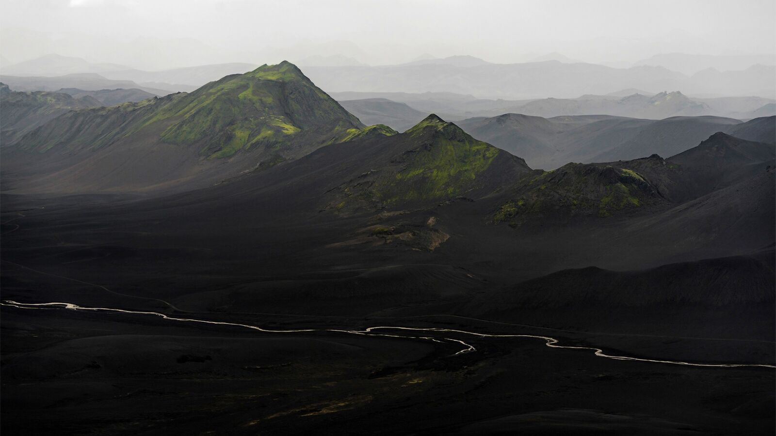 Moss-covered peaks above a black volcanic valley with a braided river, Langisjór, Iceland