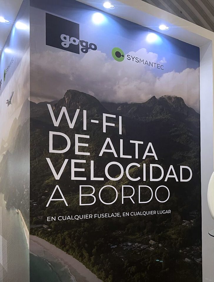 Aeroexpo booth wall co-branded Gogo and Sysmantec: a rainforest mountain photo with the headline Wi-Fi de alta velocidad a bordo