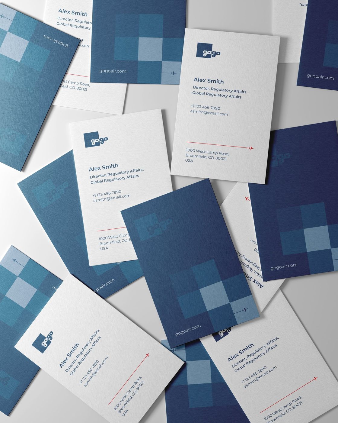 Scattered Gogo business cards: white fronts with the logo and a red flight-path line, navy backs with the square tile pattern