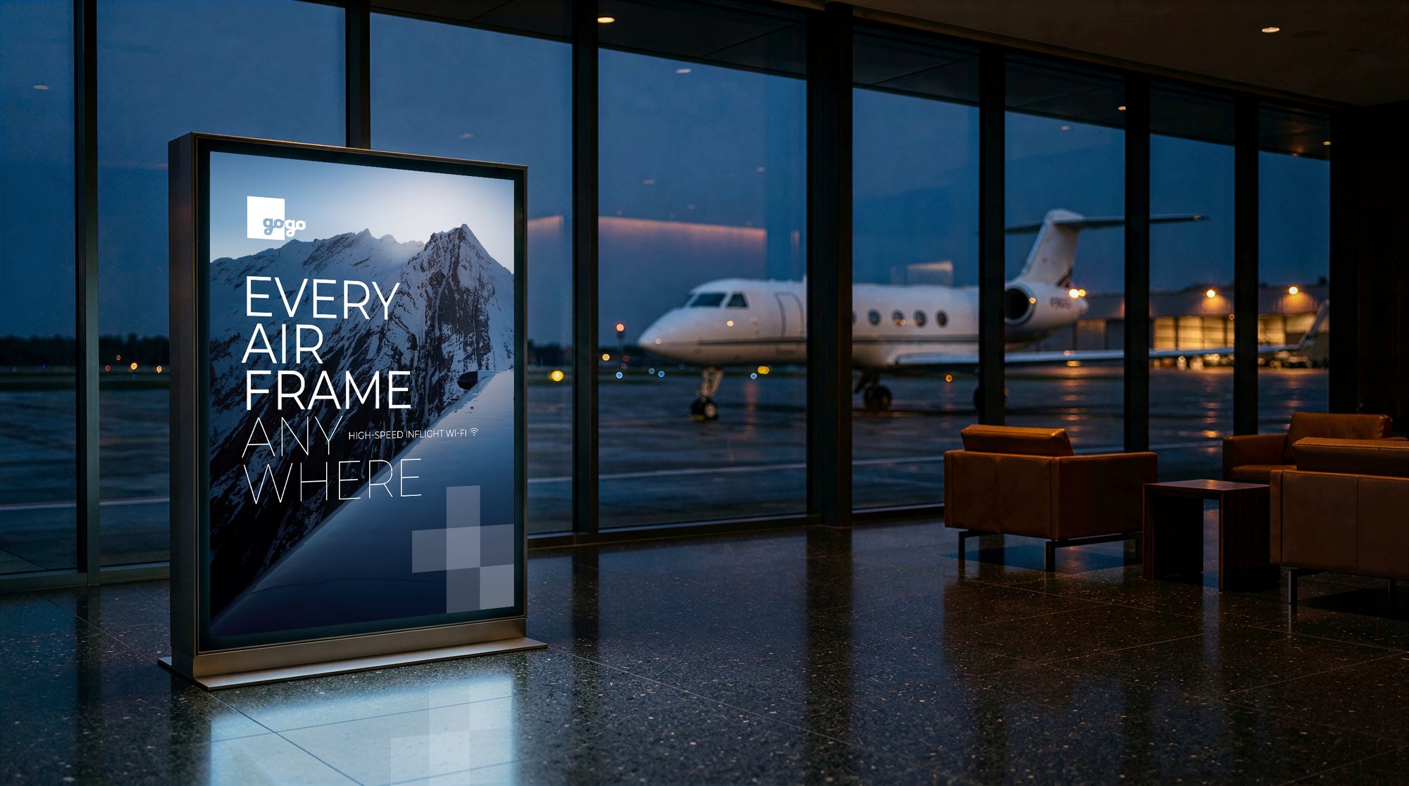 Backlit Gogo poster in a private jet terminal at dusk: a snowy mountain and the headline “Every airframe anywhere”, with a business jet parked outside the windows