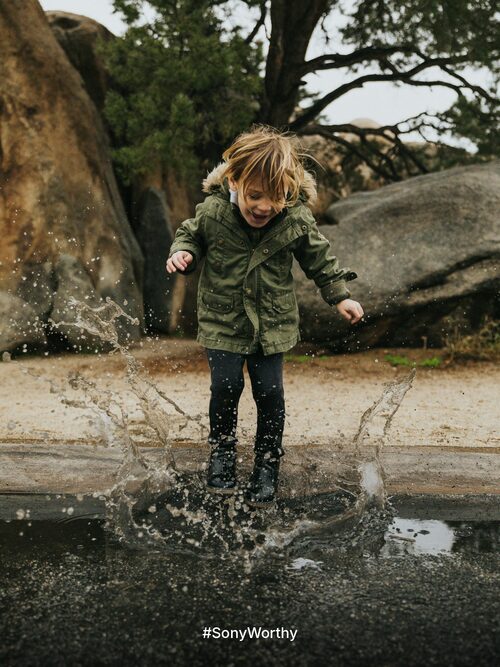Social post: a child mid-jump in a puddle with water frozen in the air, with only the hashtag #SonyWorthy at the bottom